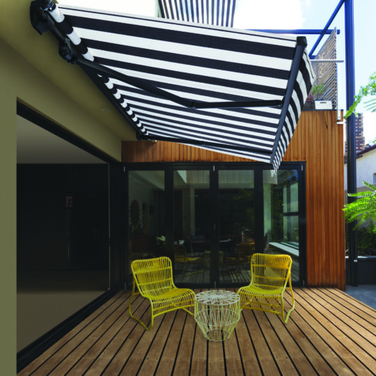 Pair of yellow cane outdoor chairs on wooden deck in contemporary courtyard